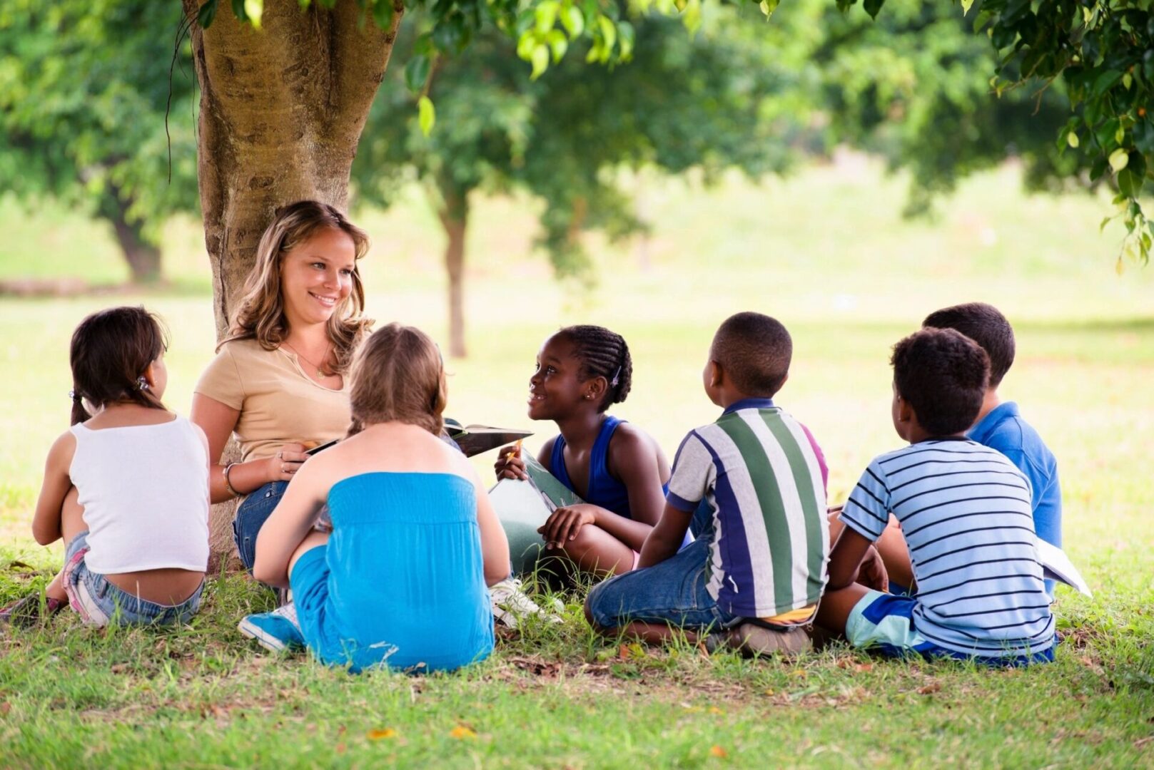 a woman is teaching kids under a tree